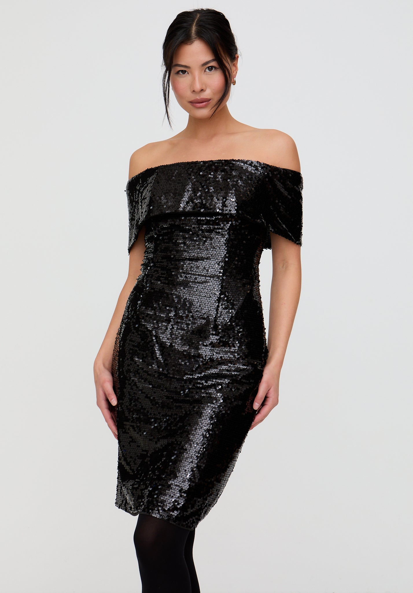 Woman wearing a black sequin off-shoulder dress on a white background