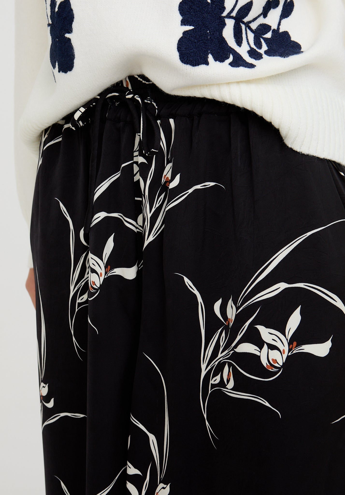 Black floral-patterned pants with a white top featuring blue floral designs.