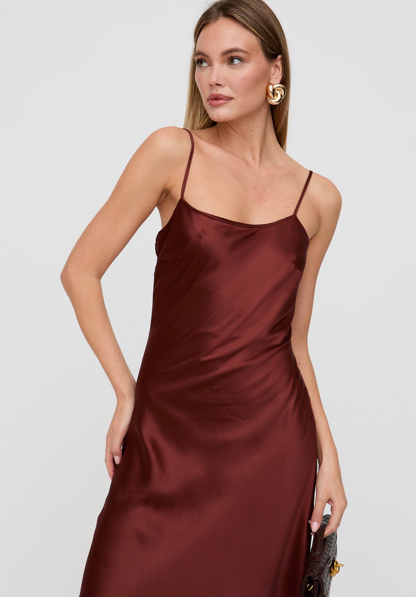Woman wearing a burgundy satin dress against a white background