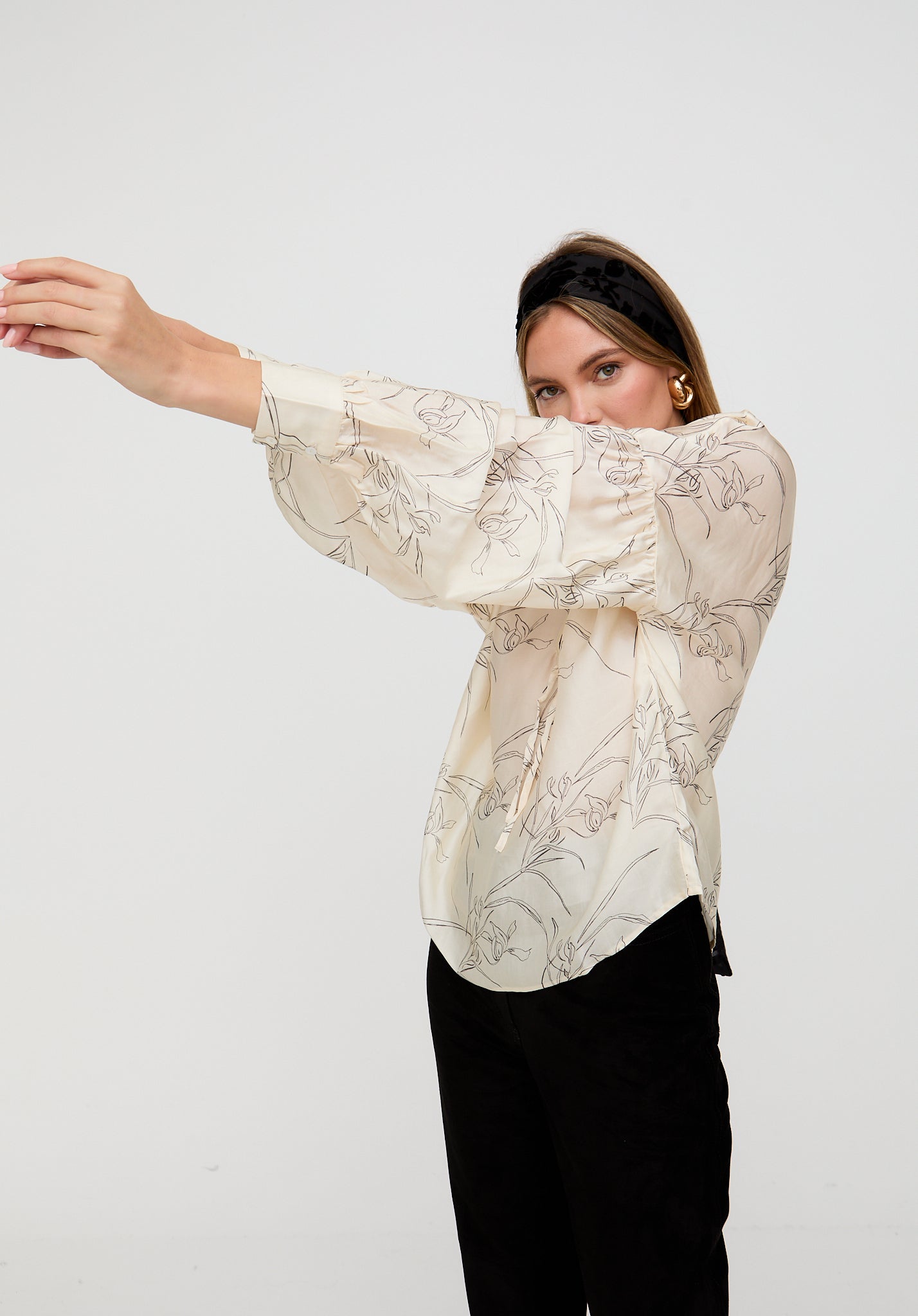 Woman wearing a cream floral blouse against a white background