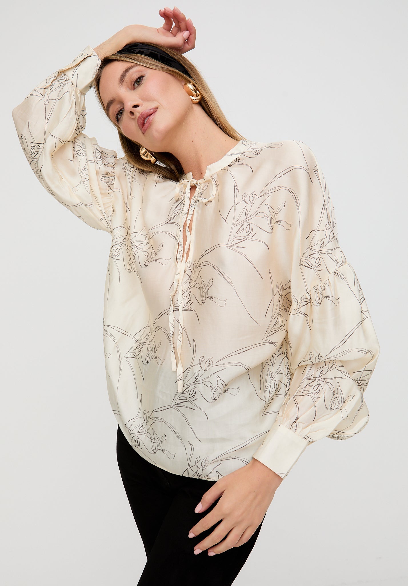 Woman wearing a beige floral blouse against a white background