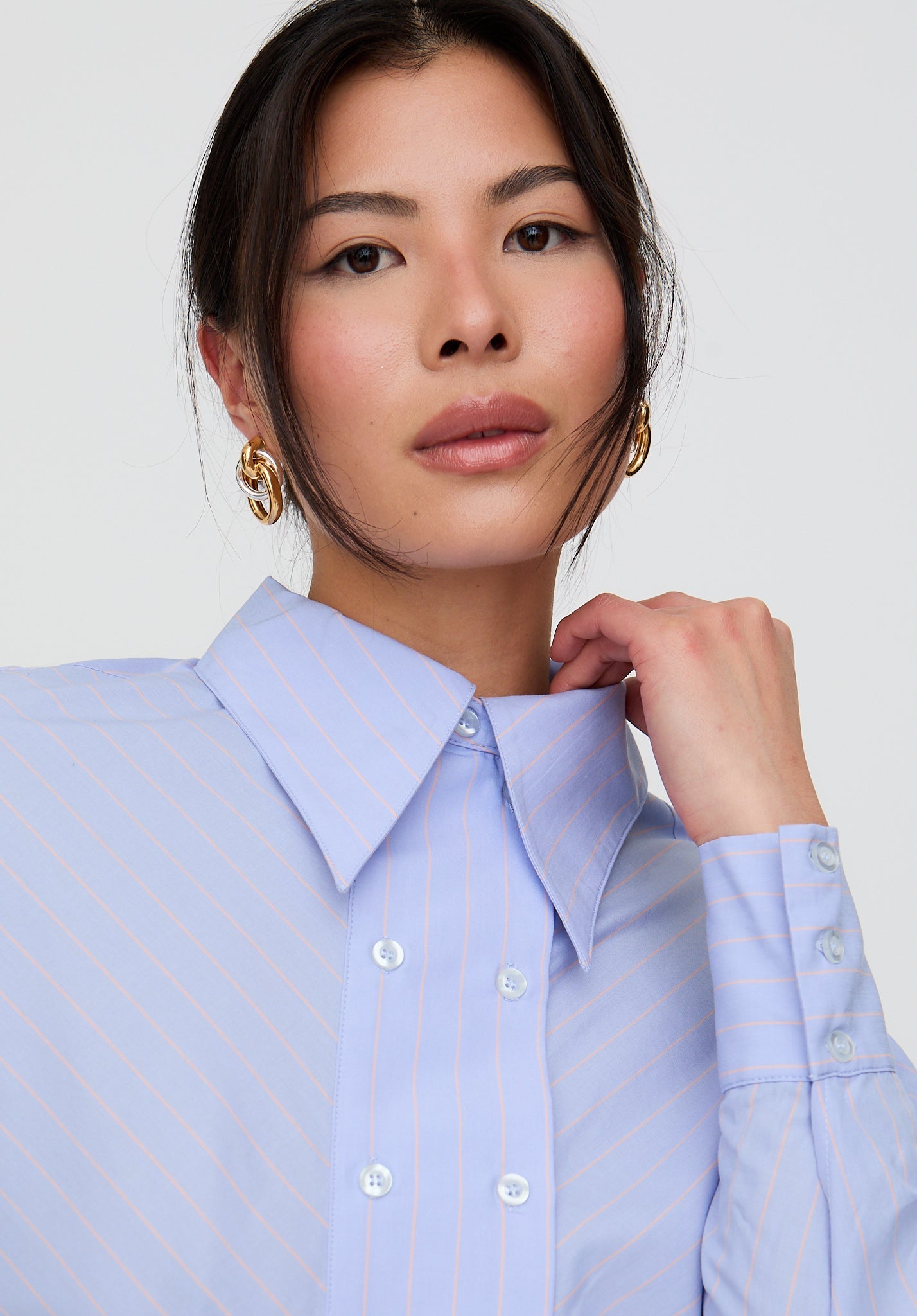 Woman wearing a light blue striped shirt against a white background