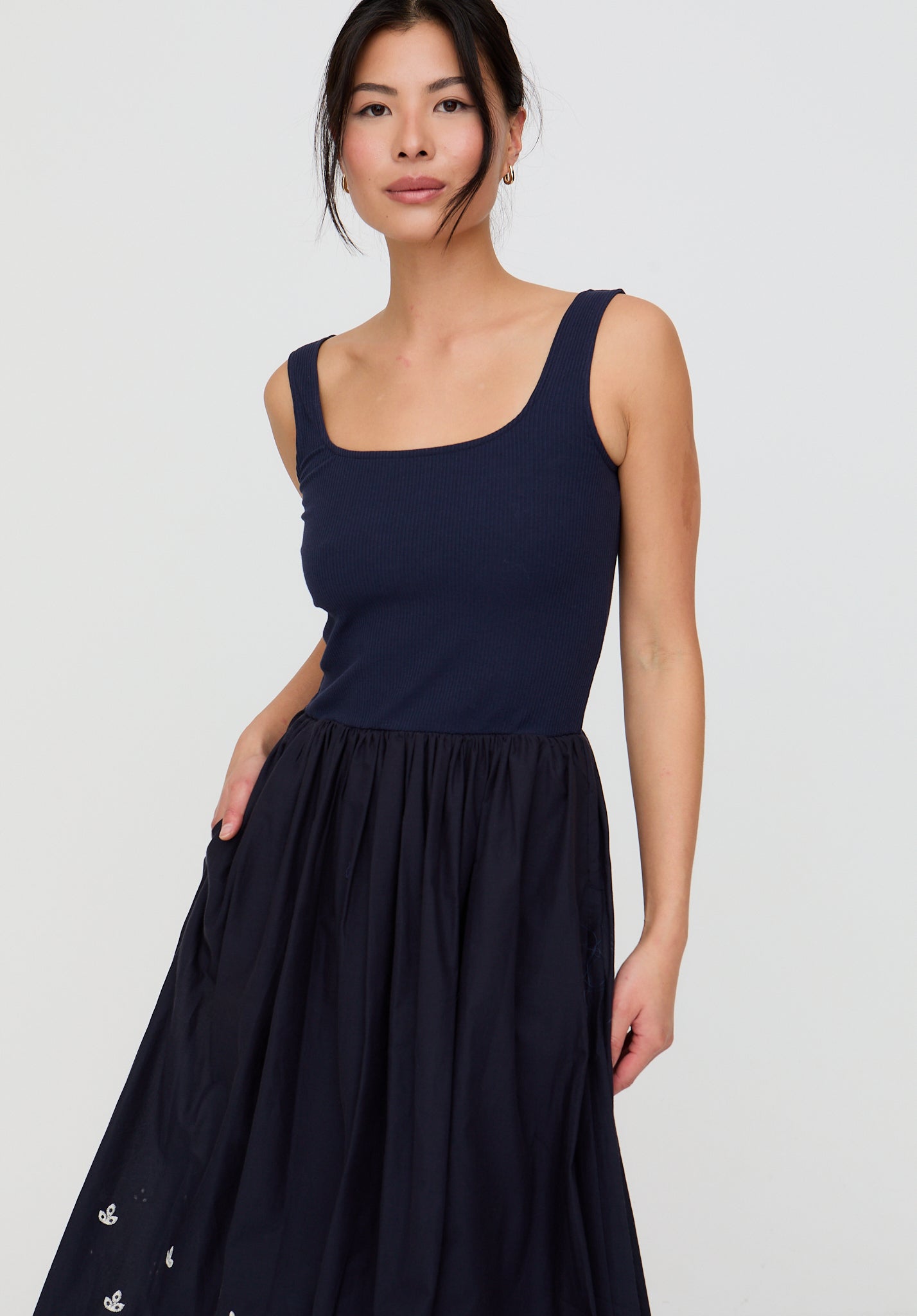 Woman wearing a black sleeveless dress with a plain background