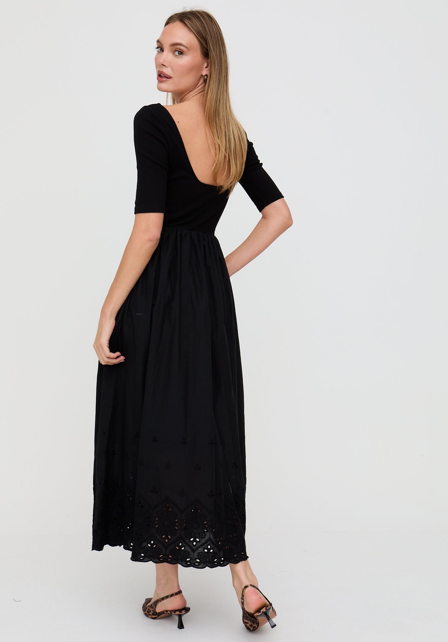 Woman wearing a black dress with lace details on a white background