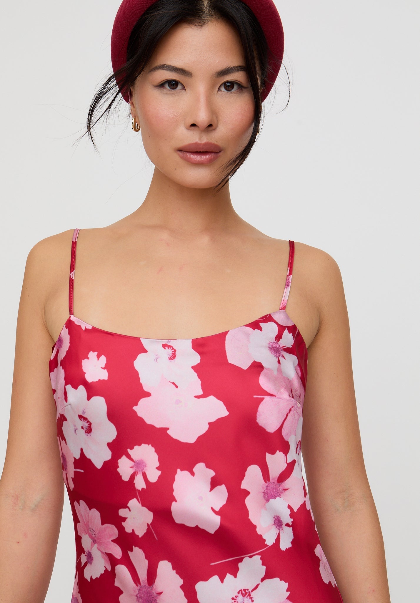 Woman wearing a red floral dress against a plain background