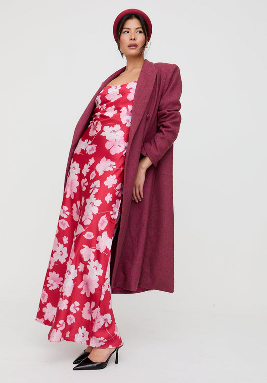 Woman wearing a red floral dress with a matching coat on a white background