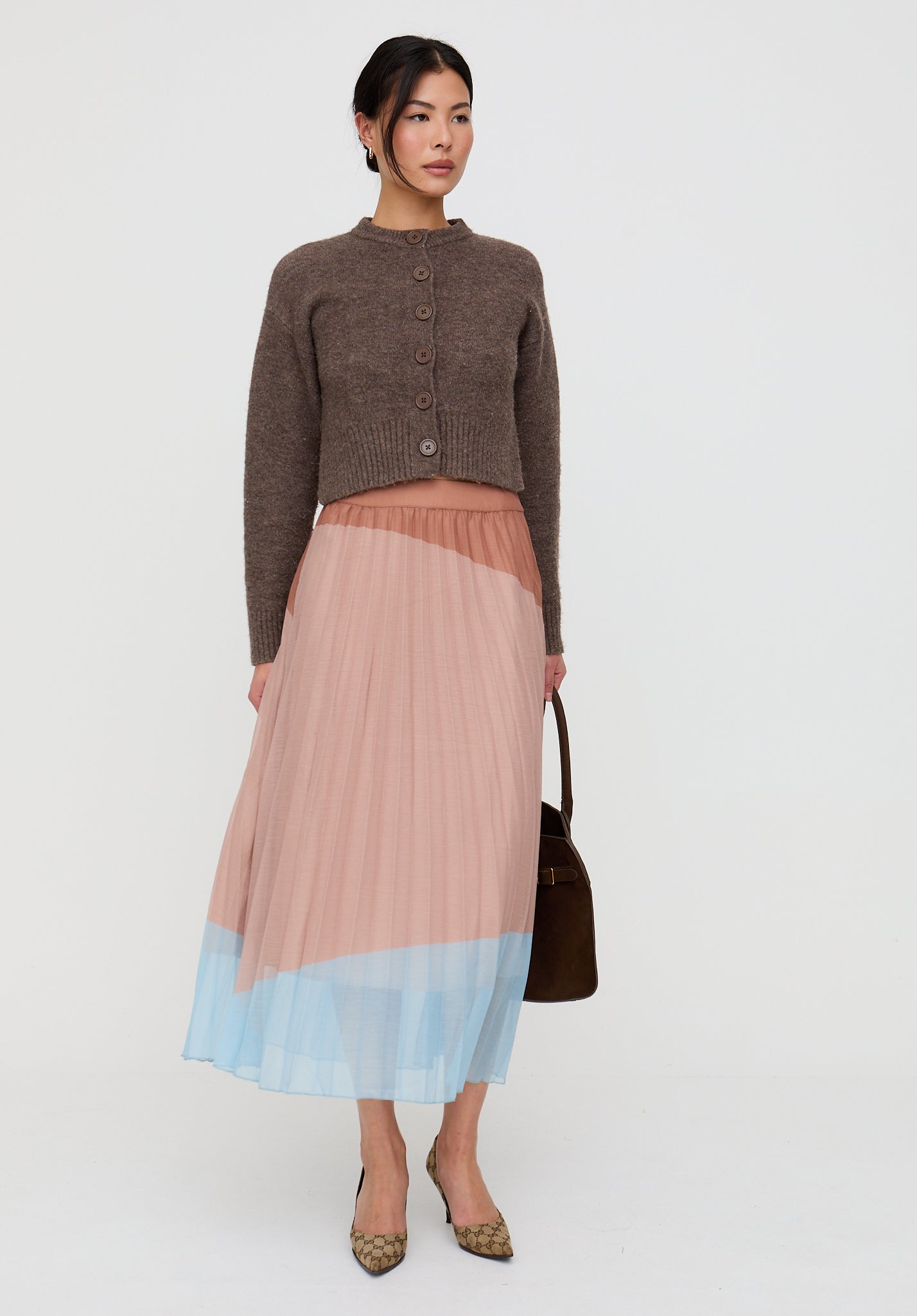 Woman wearing a brown cardigan and a two-tone pleated skirt on a white background