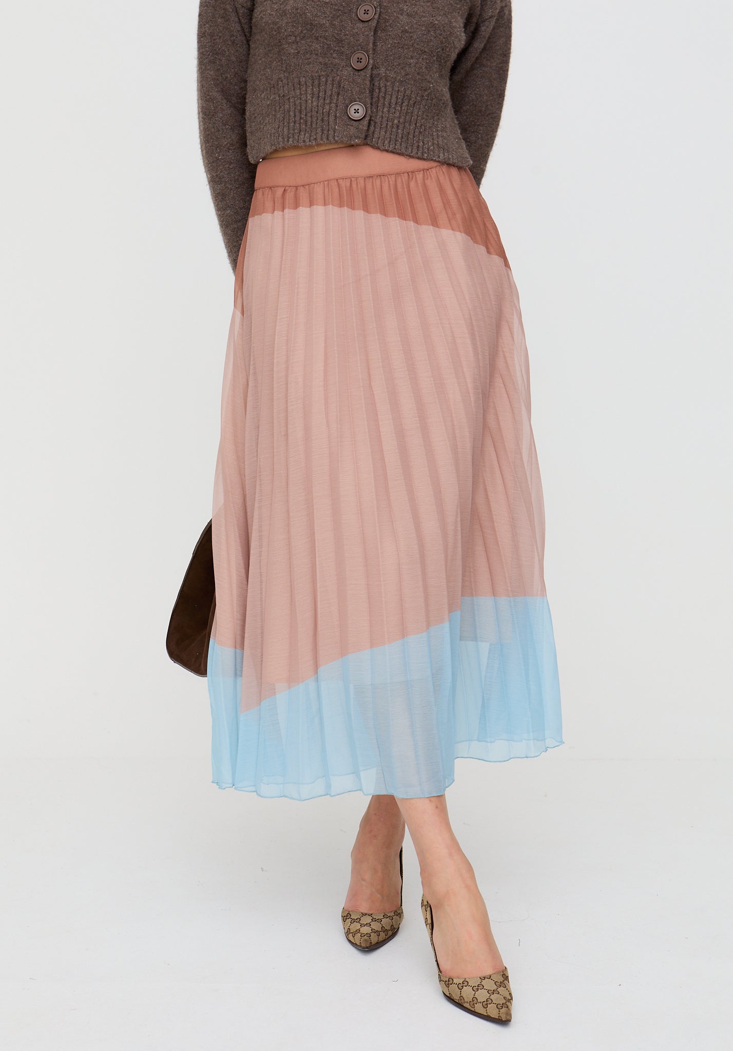 Person wearing a two-tone pleated skirt with a plain background