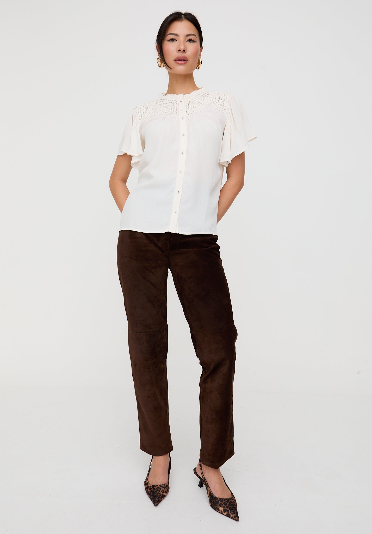 Woman wearing a white blouse and brown pants on a white background
