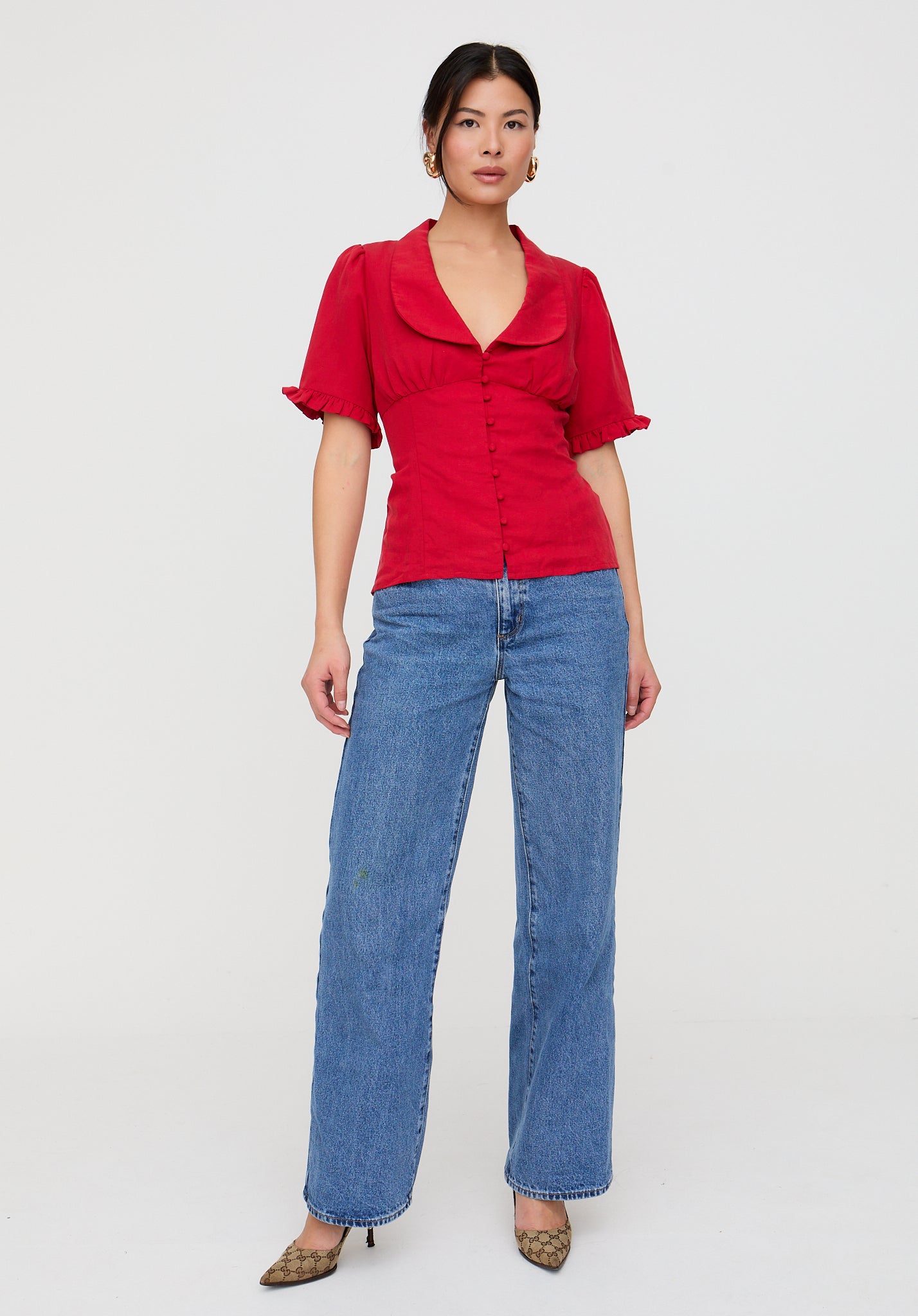 Woman wearing a red blouse and blue jeans on a white background