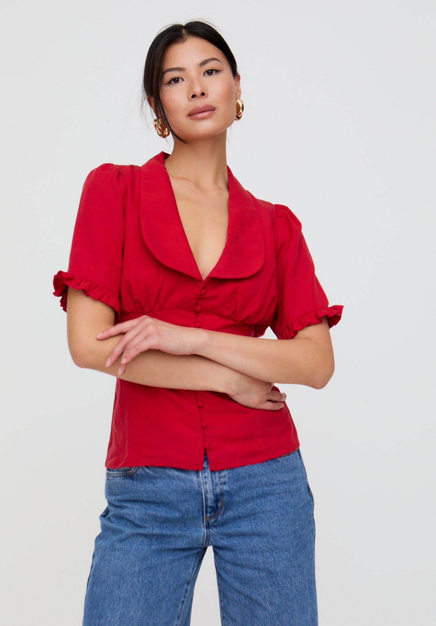 Woman wearing a red blouse and blue jeans on a white background