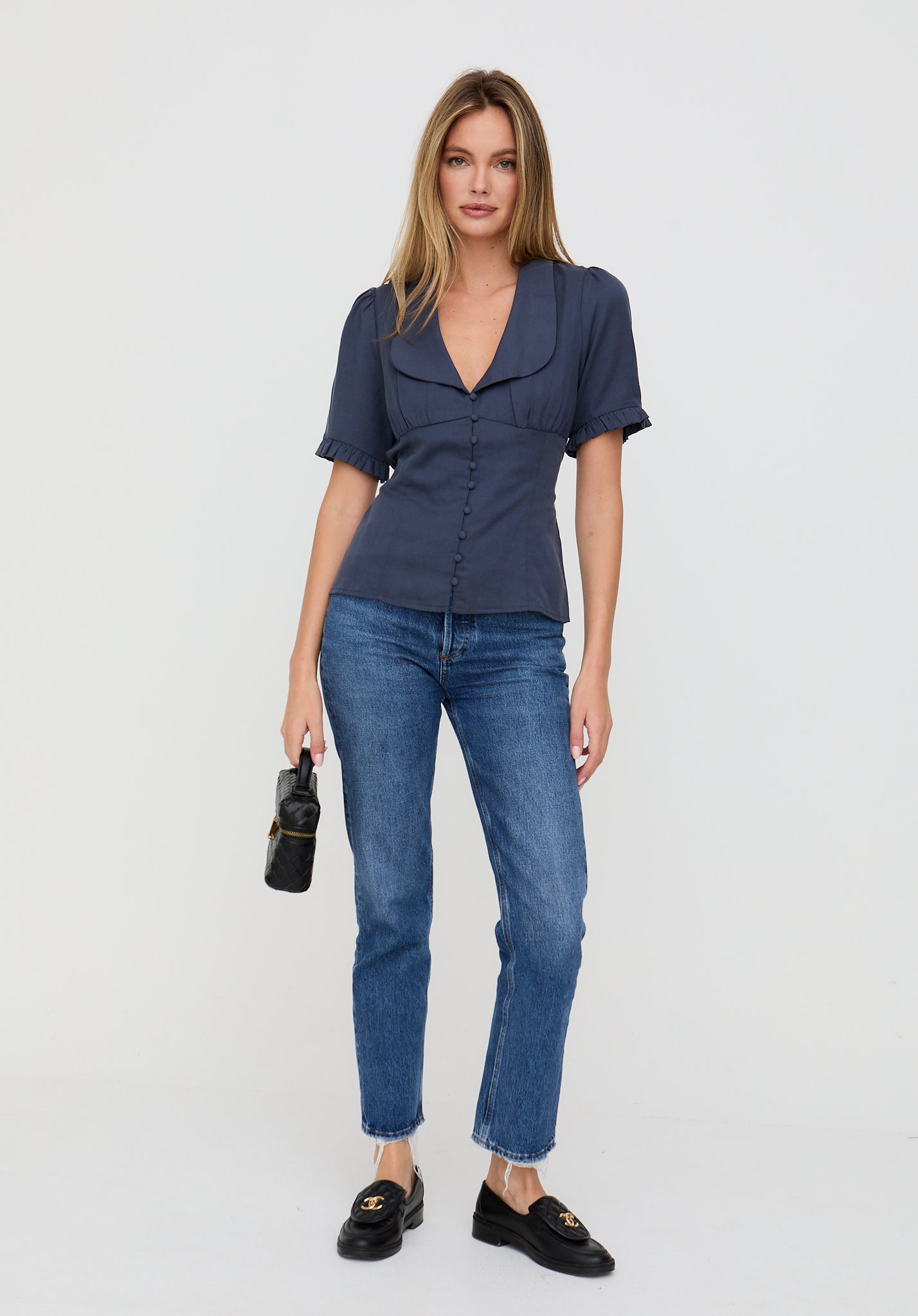 Woman wearing a navy blue shirt and jeans on a white background